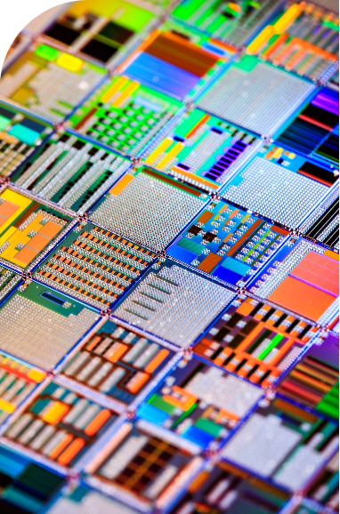 A close-up photo showing a colorful, reflective silicon wafer featuring a dense grid of microchip circuits.